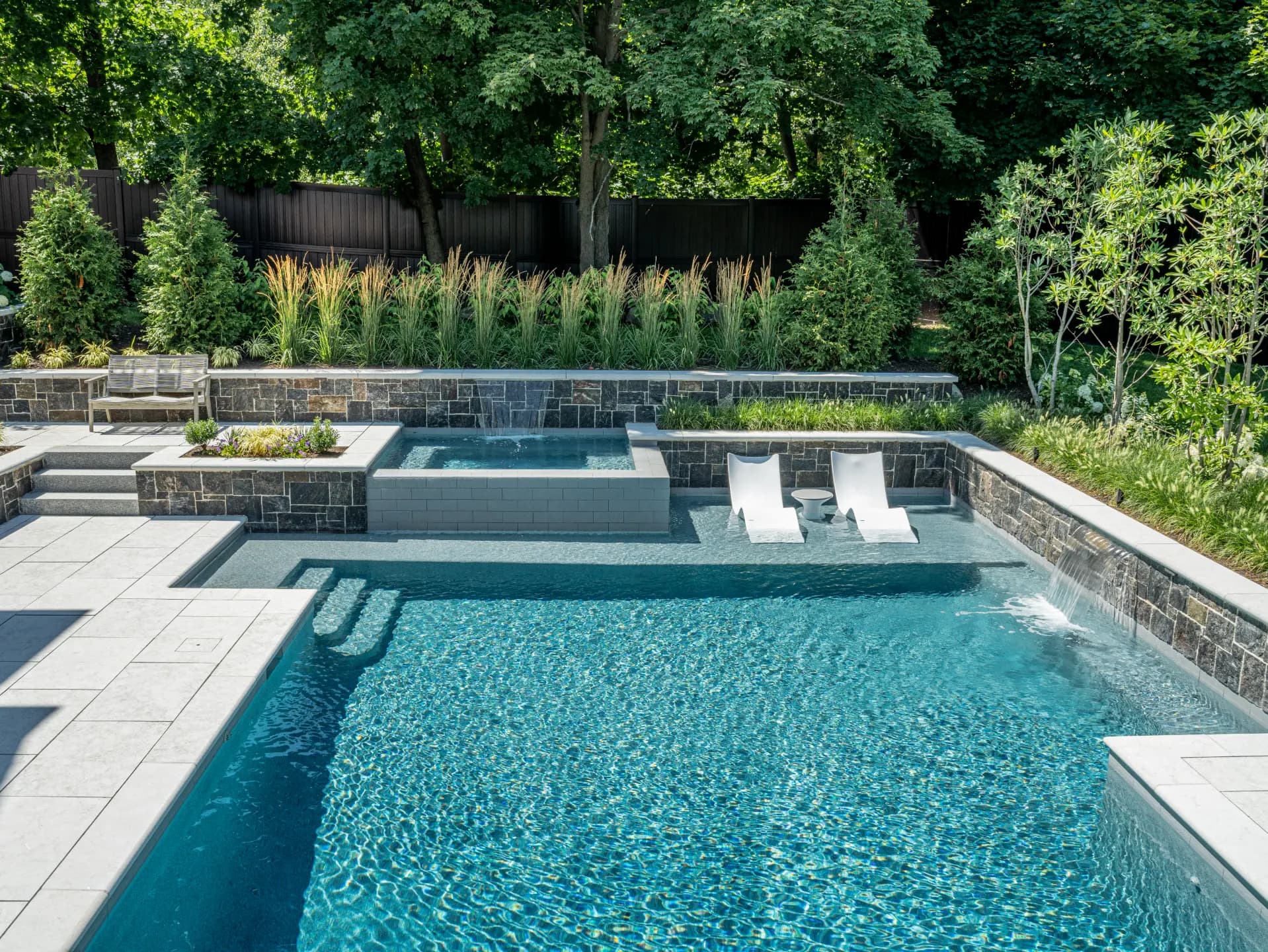 Stunning twilight shot of a finished Redwood luxury outdoor project with pool glowing and landscape illuminated